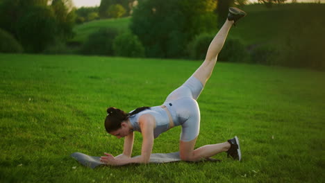 Woman-athlete-involved-in-fitness-in-park-doing-leg-lifts-on-mat.-Workout.-Work-on-a-beautiful-body-in-the-morning-or-at-sunset.-Exercises-for-leg-and-hip-muscles